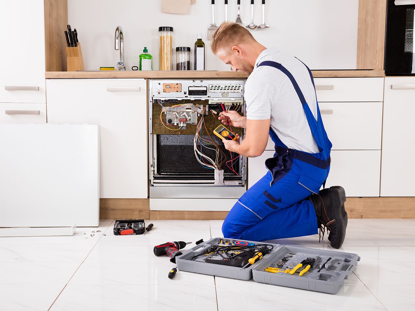 Ein Handwerker in Arbeitskleidung arbeitet an der Reparatur einer Spülmaschine