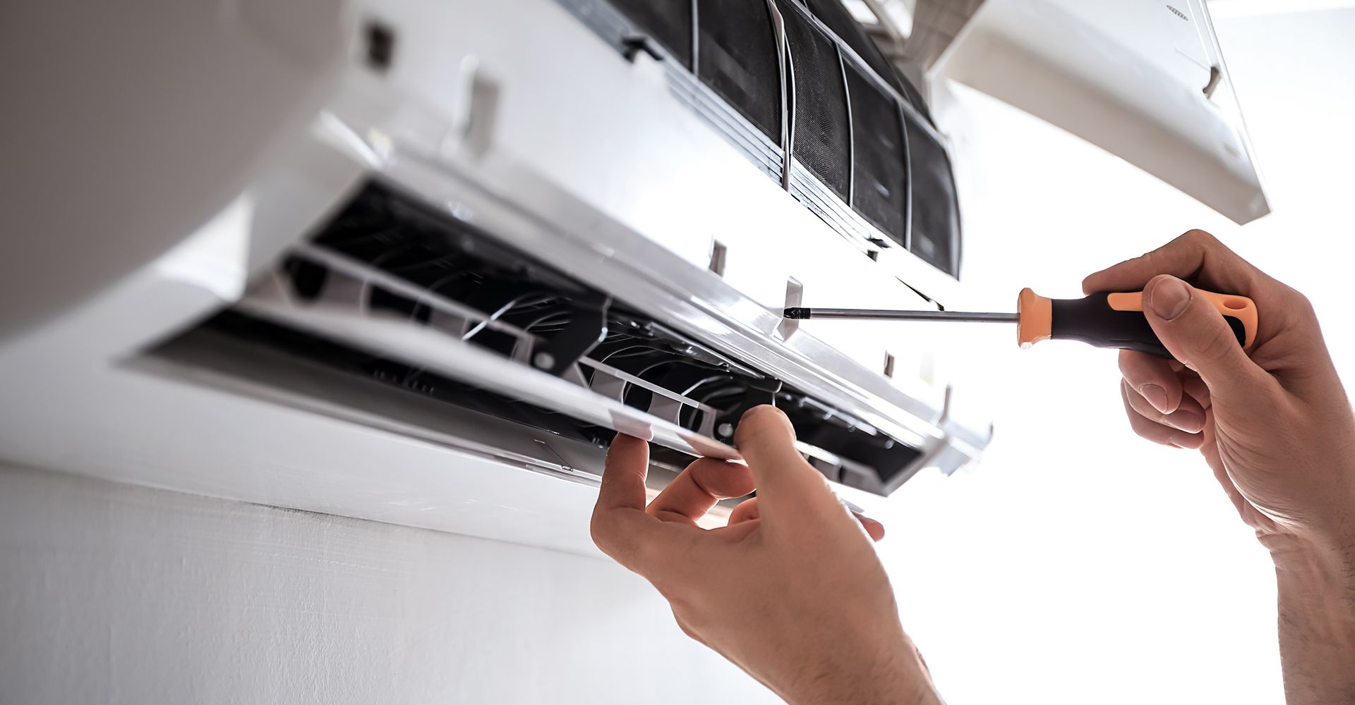 Techniker arbeitet an einer Klimaanlage, um deren Funktionalität zu gewährleisten.